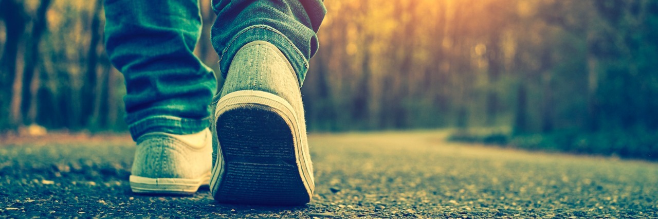 Becoming My Own Advocate Changed My Perspective of My Stutter Person wearing jeans and sneaker shoes, walking on tree-lined path