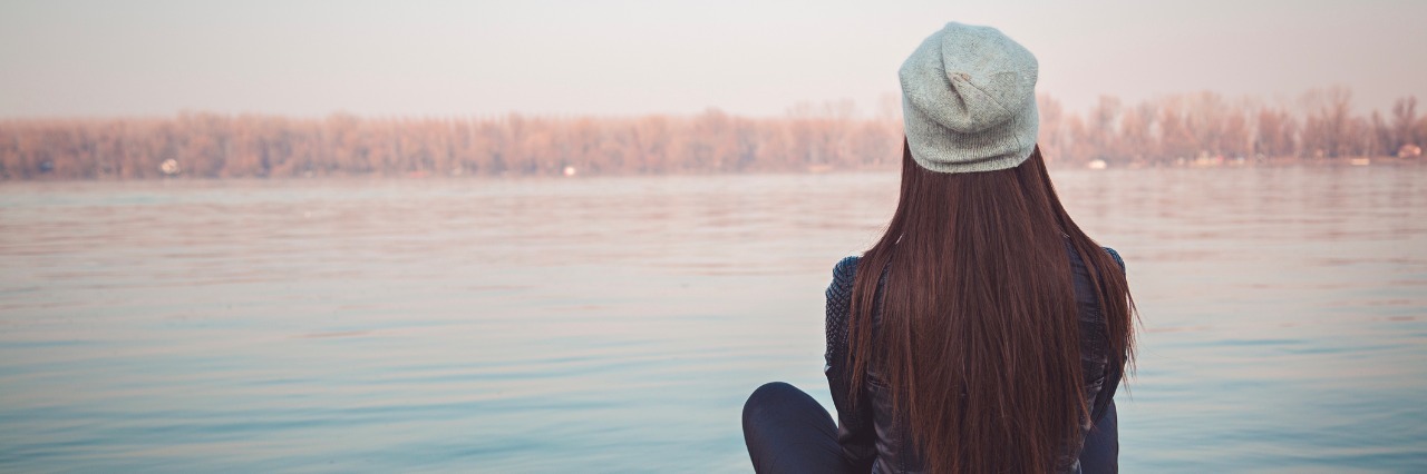 Anxiety and Fear of the Future Girl sitting on pier and lookingat the river