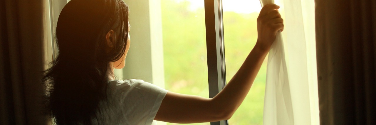 What a Good Day With Chronic Pain Feels Like woman opening curtains and looking out window