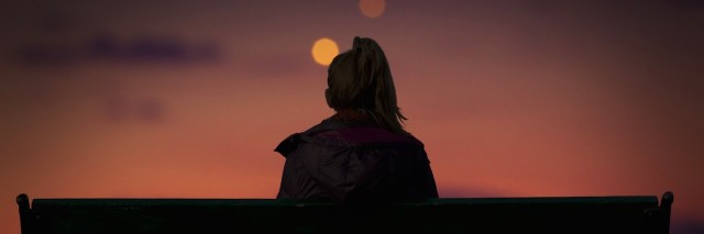 Silhouette of a girl watching city lights on a bench
