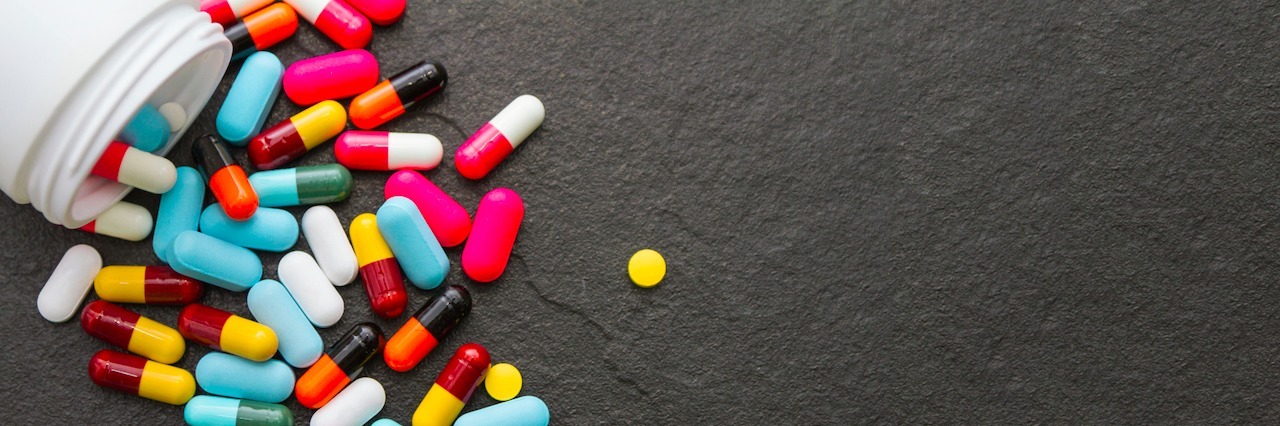 What to Know When You Start Taking Medication for a Mental Illness pills spilled out on a black surface