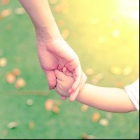 Parent holding baby's hand outdoors