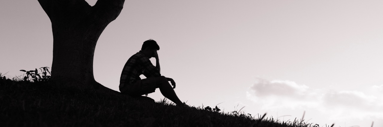 Depression: What I Wish I Knew About Recovery sad young man sitting under a tree in the park