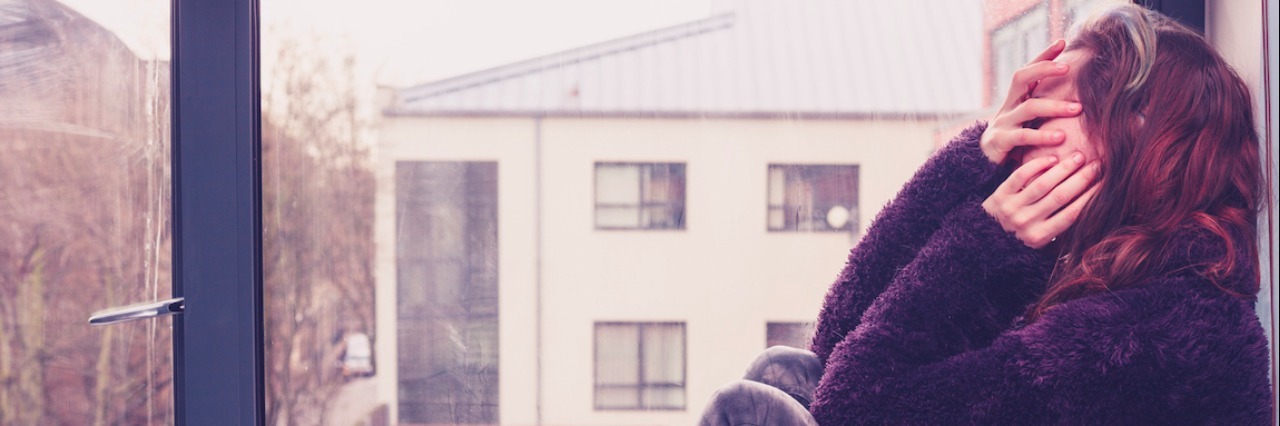 Why We Should Stop Romanticizing Anxiety Sad young woman is sitting by the window