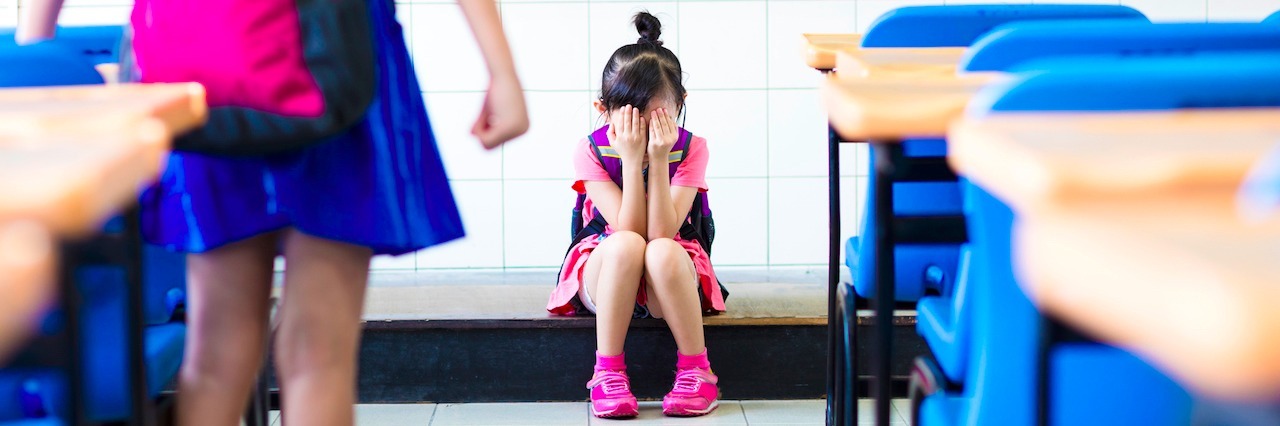 Reaction to Cancer Survivor Bethany Thompson's Suicide young girl in a classroom sitting on the floor covering her face with her hands