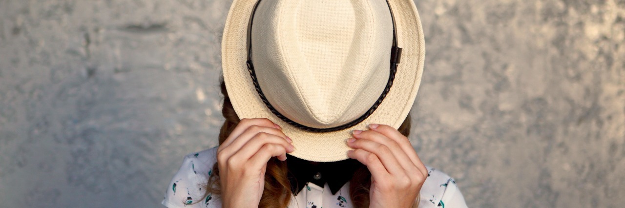 Things I Never Thought I'd Do Because of Sjogren's Syndrome woman hiding face with hat