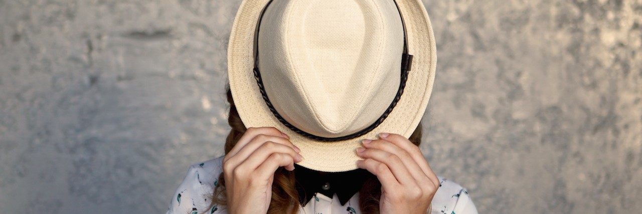 a woman hiding behind her hat