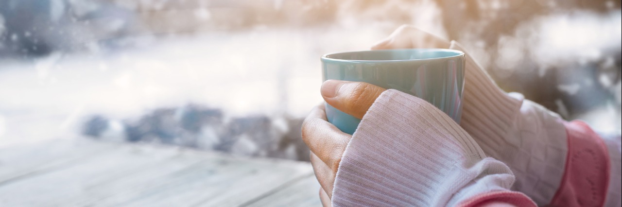Holiday Season Tips and Advice for People Who Are Sick woman's hands holding warm cup of coffee outside in the snow