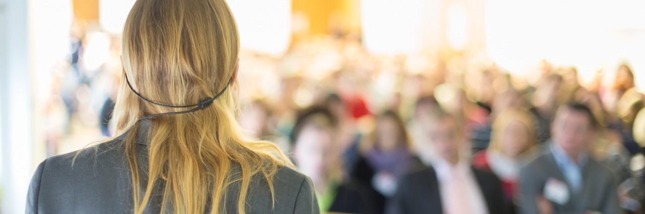 Ulcerative Colitis: Leadership Roles and Chronic Illness or Disability woman speaking into a microphone and leading a business conference