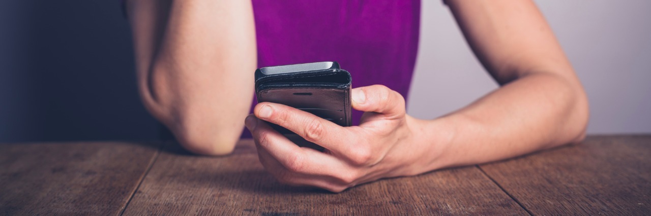 Borderline Personality Disorder: The Worst Thing Friends Can Say to Me woman sitting at a table and looking down at her smartphone