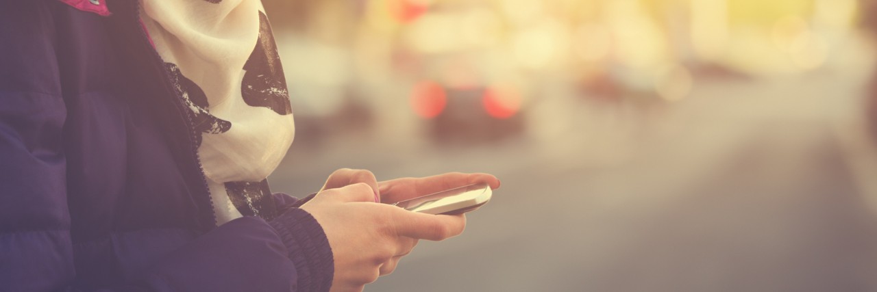 Close-up photo of hands holding a cell phone on the street