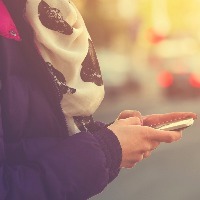 Close-up photo of hands holding a cell phone on the street