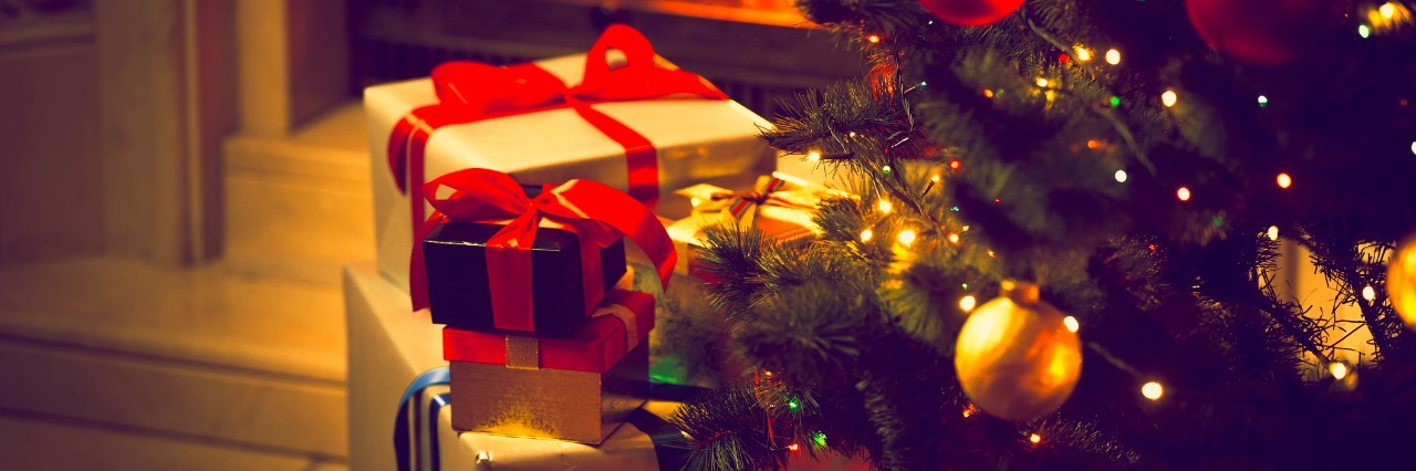 How to Reduce Holiday Stress for Loved One With Chronic Pain Toned photo of decorated Christmas tree and gift boxes against burning fireplace