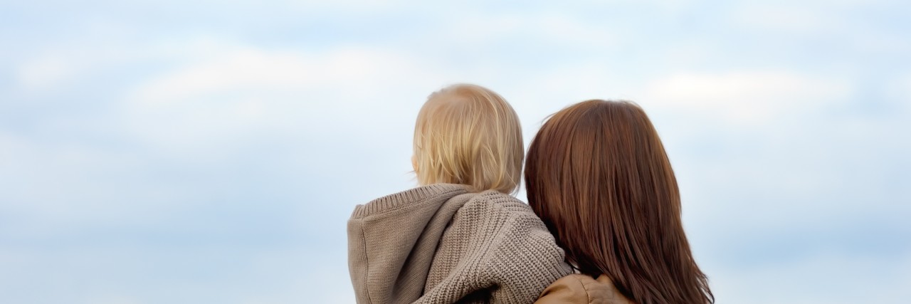 Woman holding toddler with airplane on background