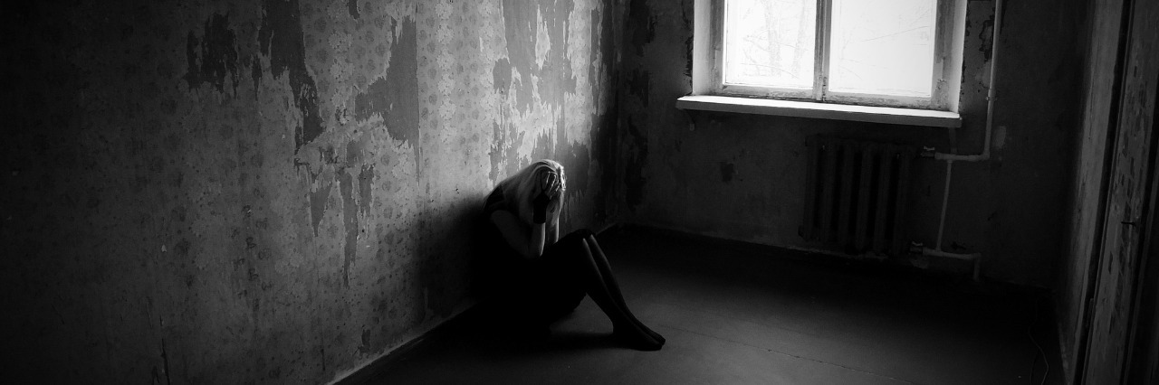 How I Survived Isolation Because of Mental Illness sad girl sitting on the floor in the corner of a small dark room