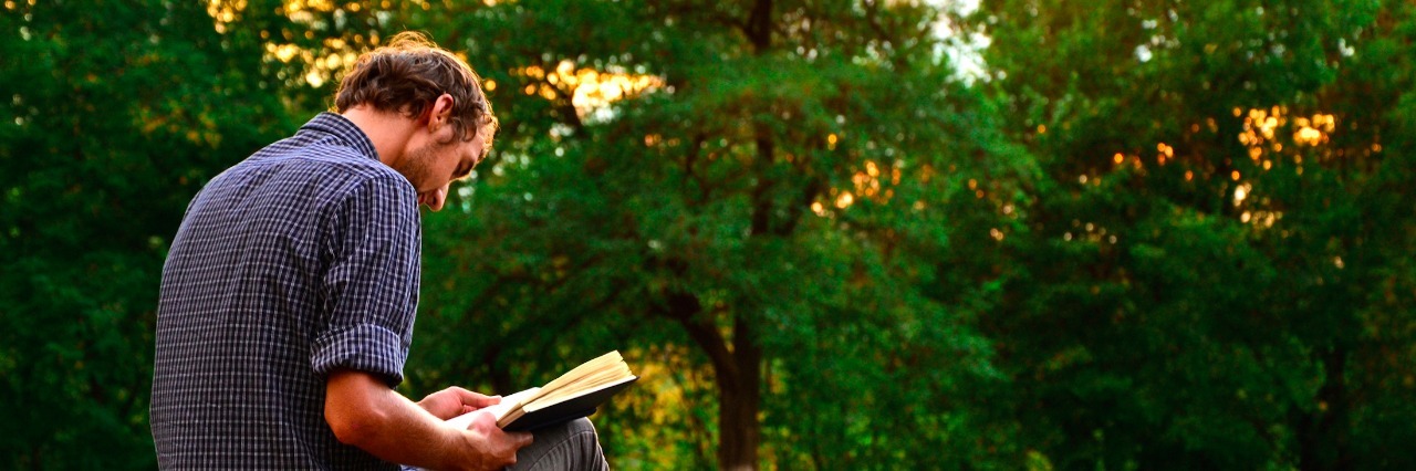 Guy reading book in the park