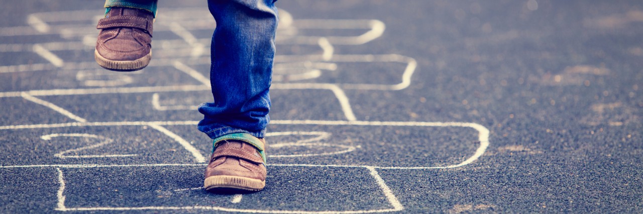 Balancing Health and Quality of Life With Primary Immunodeficiency Child playing hopscotch on playground outdoors.