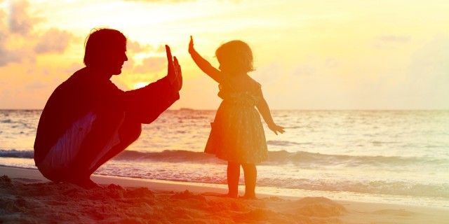 parent high fiving young daughter at the beach