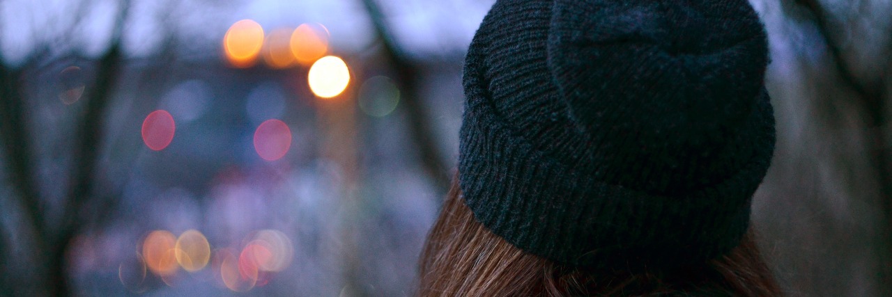 girl in winter clothing looking towards city lights