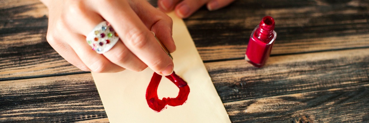 A woman painting a heart on a piece of paper