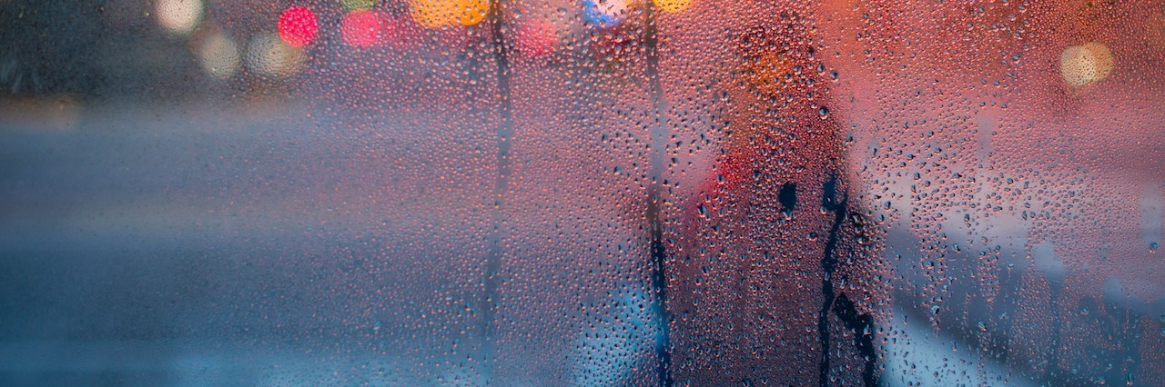 image of a woman in the rain through a glass window