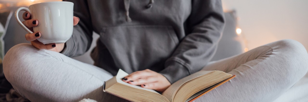 The Importance of Spoonie Self-Care After This Stressful Election Girl drinking hot tea and reading book in bed