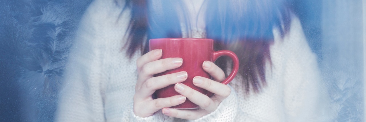 What to Remember on the Days Depression Leaves You Feeling Defeated a woman holding a mug and looking out a window