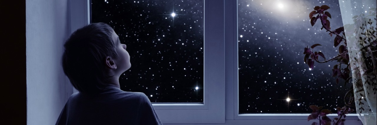 Autism as a Strength little boy looking out a window at the night sky