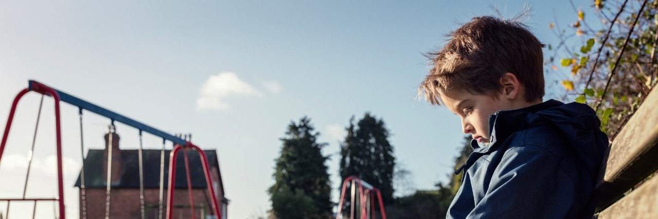 Autism: When People Judge Children With Behavior Challenges sad boy sitting on a bench by a playground