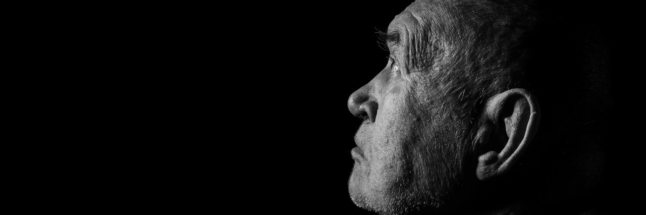 Feeling Alone With Mental Illness senior man looking up in dark monochrome image