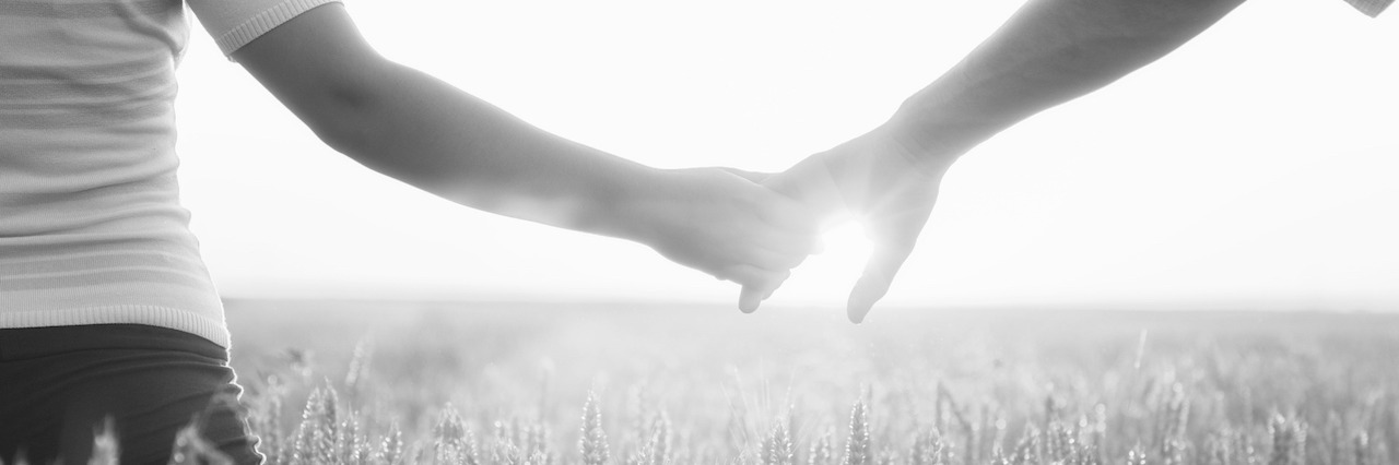 Tips for Loving Someone With PTSD A couple holding hands in a field