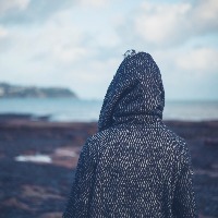 Woman in hooded coat walking on beach