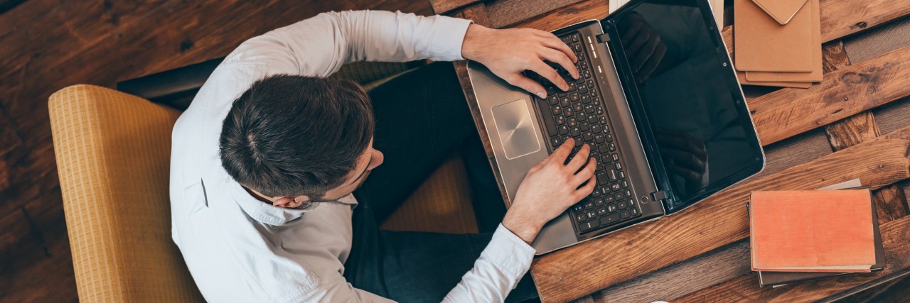 Top view of young man working on laptop while sitting at his working place