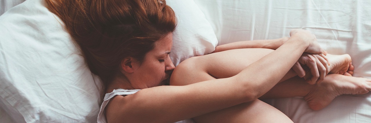 young woman curled up in bed