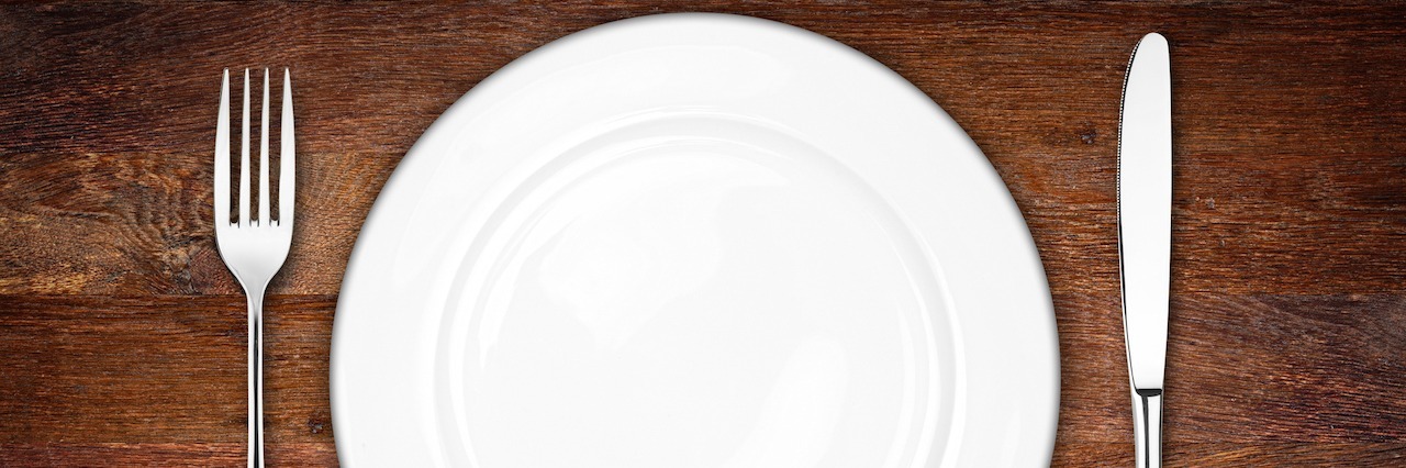 place setting with empty dish fork and knife on wooden background