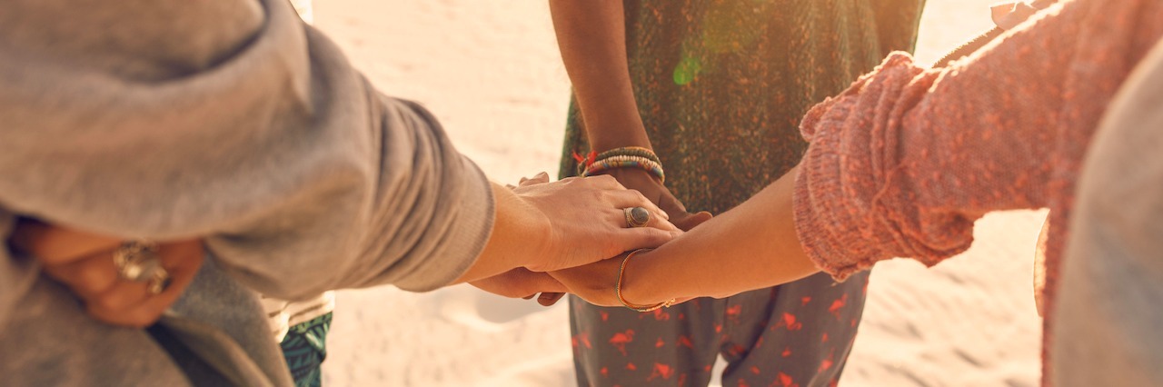 How to Be a Friend to Someone Struggling With Social Anxiety A group of friends at the beach reaching out their hands
