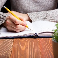 Woman writing in notebook with pencil