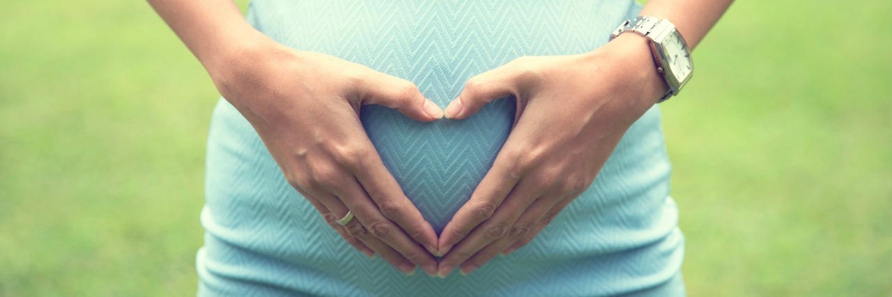 woman with a heart over her pregnant belly