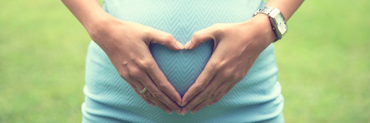 Why It's Important to Talk About Grief After Your Baby Is a Stillborn woman with a heart over her pregnant belly
