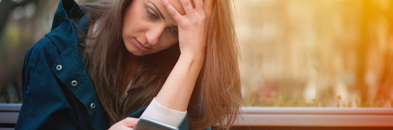 My Daughter With Autism: How a Cellphone Helps Me Support Her stressed girl sitting on a bench looking at her cellphone