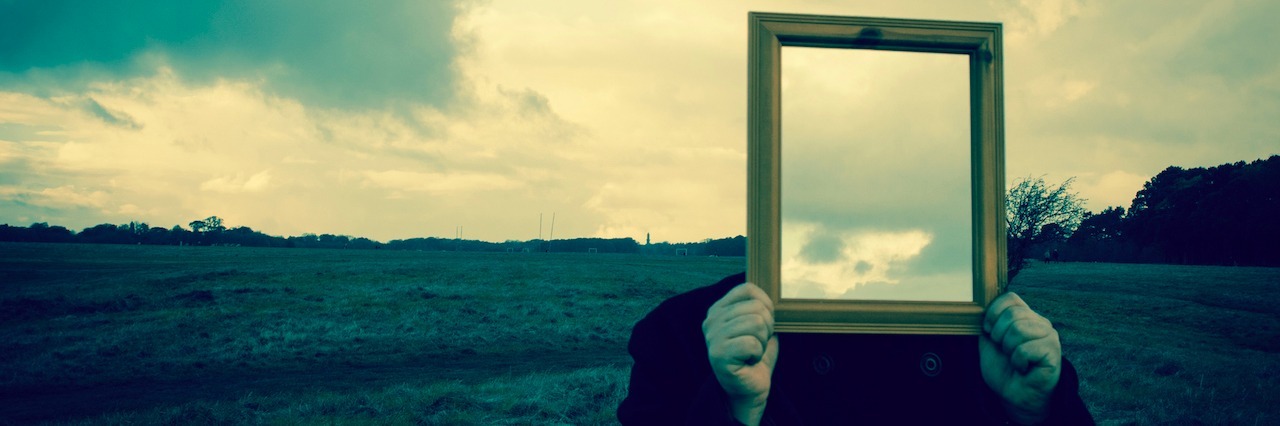 What My Life Looks Like Living With Borderline Personality Disorder A man holding up a mirror over his face ,which reflects the sky