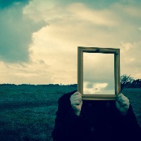 Man with mirror in front of face, reflecting sky