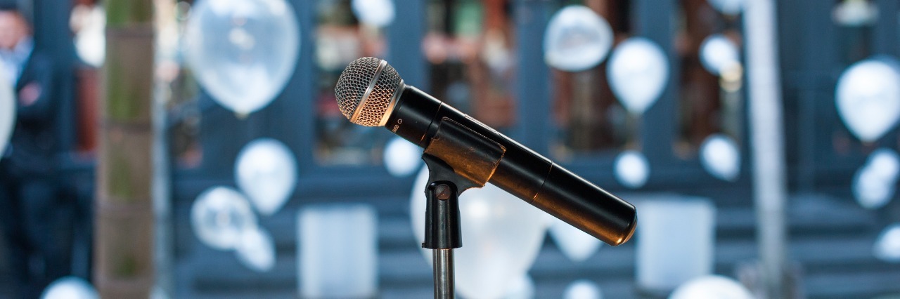Man Promotes Mental Health Awareness in Wedding Speech microphone on stand with wedding decorations in the background