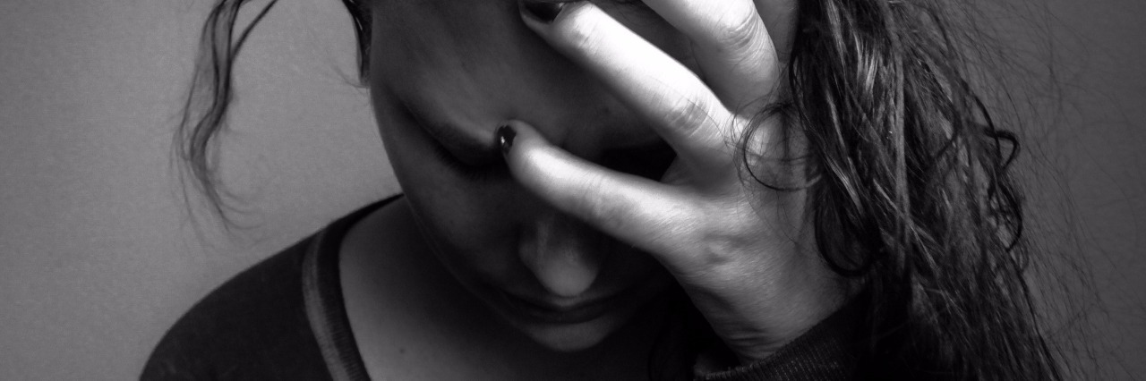 Migraine Symptoms Beyond Headaches black and white photo of woman holding her head with a pained expression