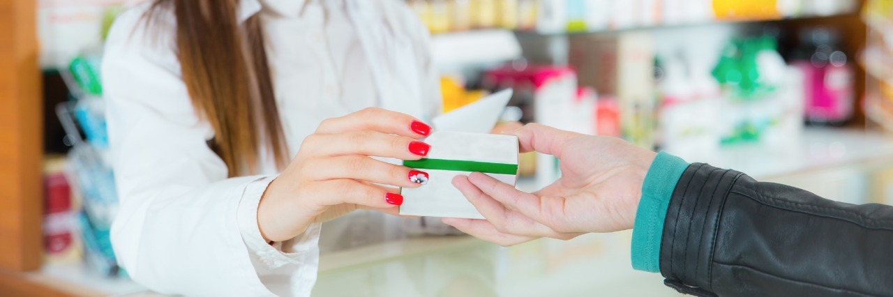 pharmacist handing a customer a prescription