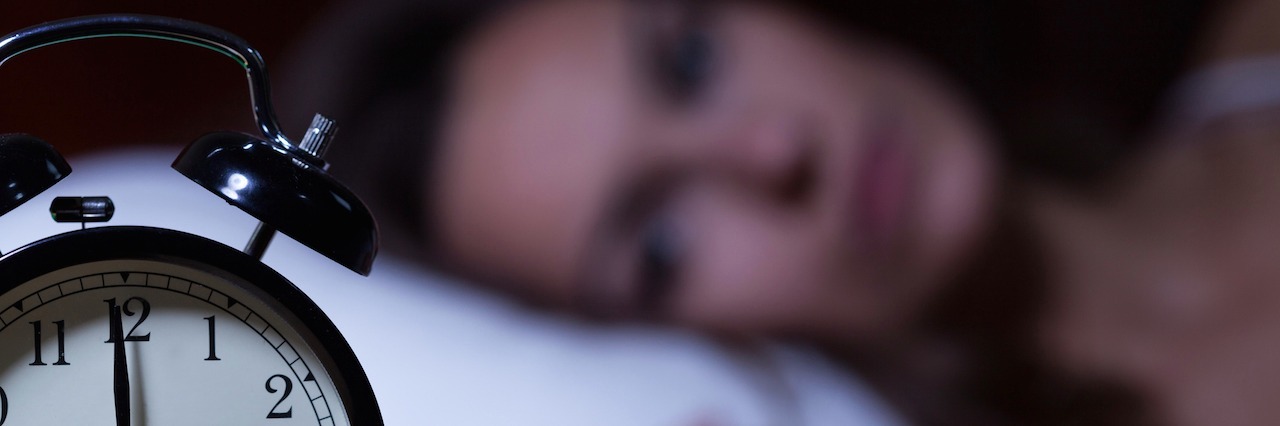 Experiencing Early Morning Suicidal Thoughts After You Have a Baby woman in bed looking at her alarm clock