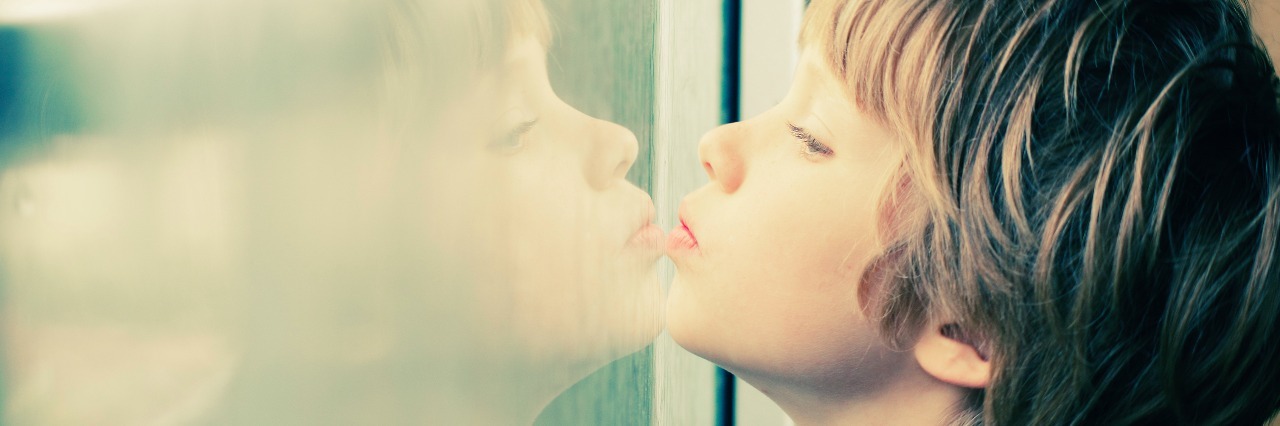Autism: What I Wish Others Understood About My Son's Needs a young boy looking at his reflection in the window