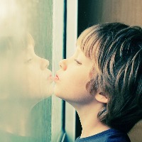 a young boy looking at his reflection in the window