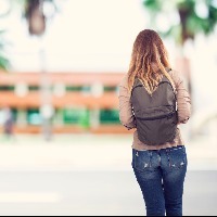 female student walking to school wearing a backpack