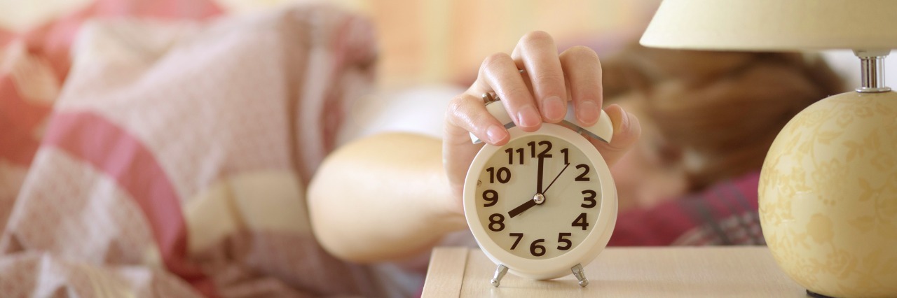 Symptoms of Chronic Fatigue Syndrome in the Morning girl turning off alarm clock waking up in the morning